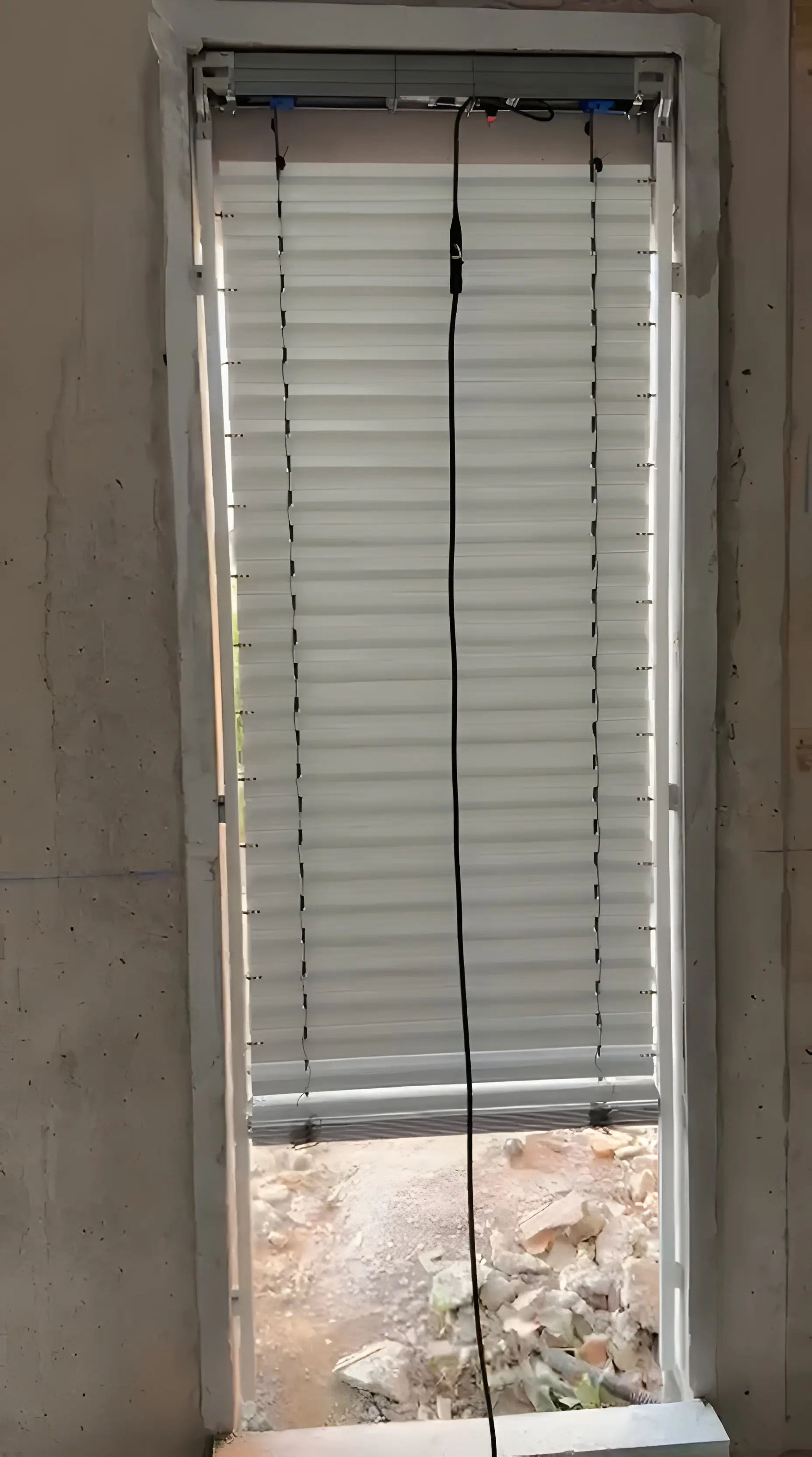 Brise-soleil orientable aux lames aluminium descendues et fermées dans une ouverture de mur en béton brut